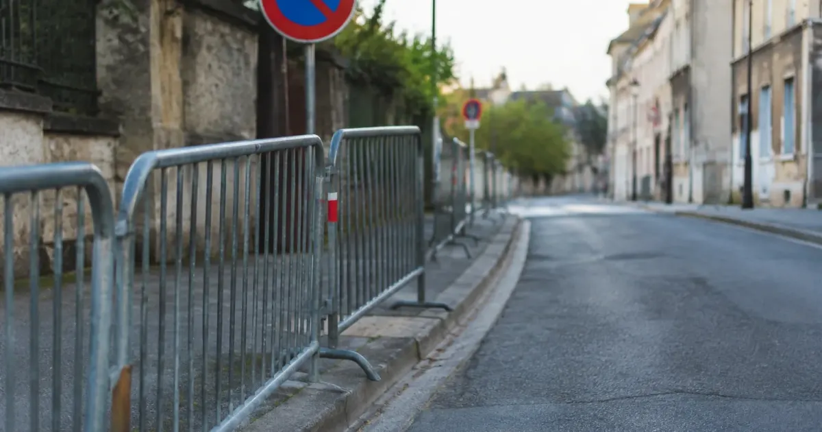 Rue déserte avec barrières métalliques et panneau de signalisation