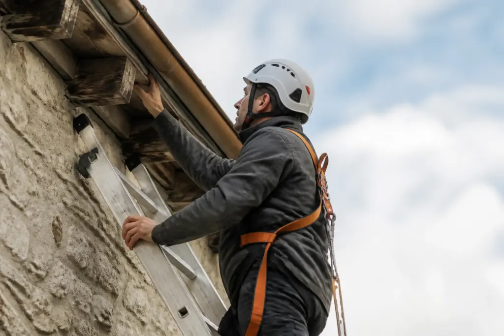 Technicien avec harnais inspecte abergement depuis echelle stable